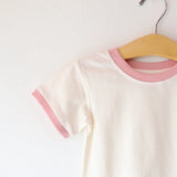 White t-shirt with pink trim on a hanger against a white background